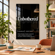 Unbothered Definition glass wall art by Artdesigna, black and white typography print in a home office