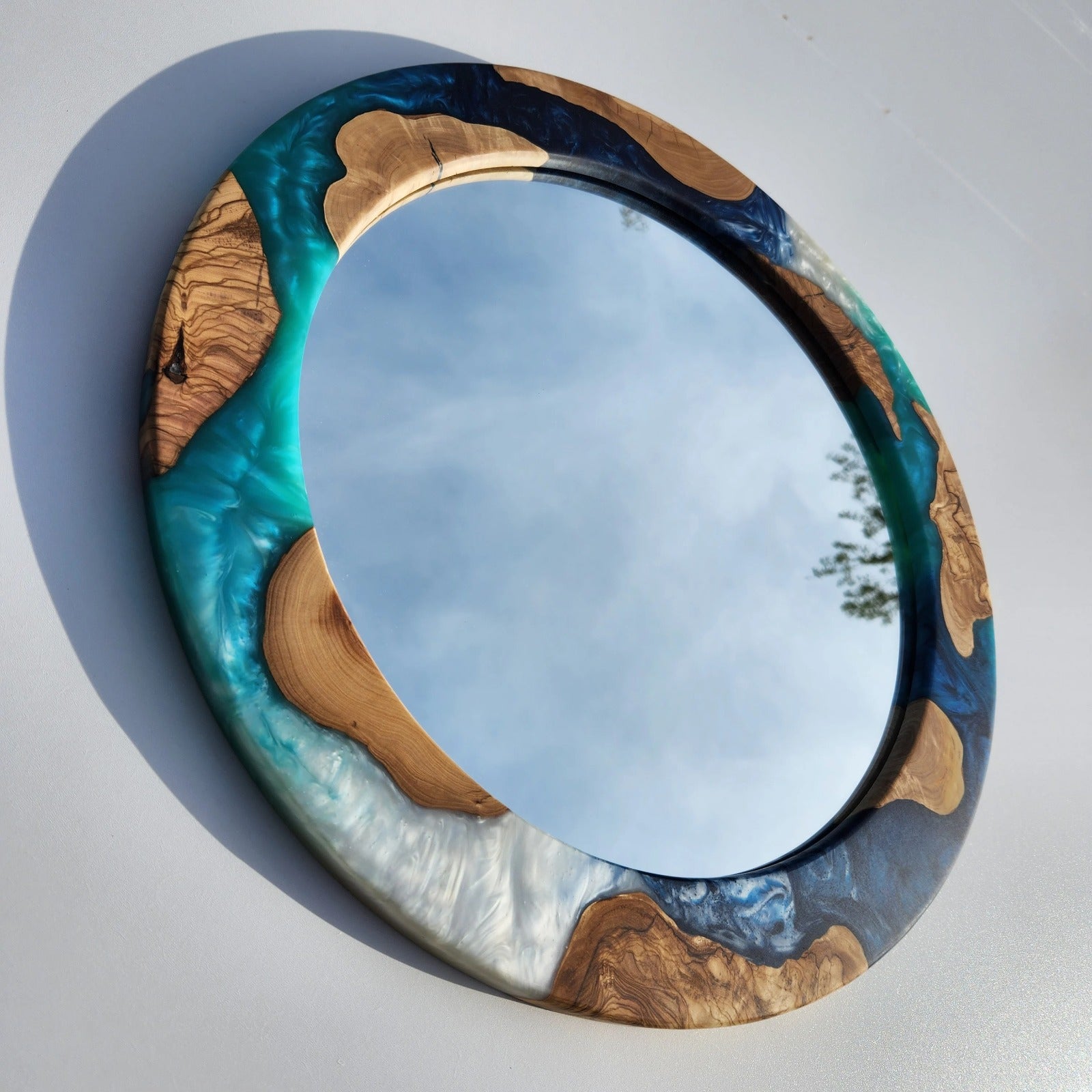 Ocean-inspired epoxy and olive wood wall art mirror featuring a natural wood frame and ocean blue epoxy accents.